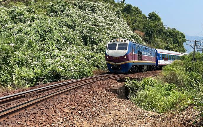 Đoàn tàu chạy trên đường ray uốn cong qua triền đồi xanh — ẩn dụ cho việc phòng khám mới mở cần đặt đúng "đường ray" vận hành ngay từ đầu.